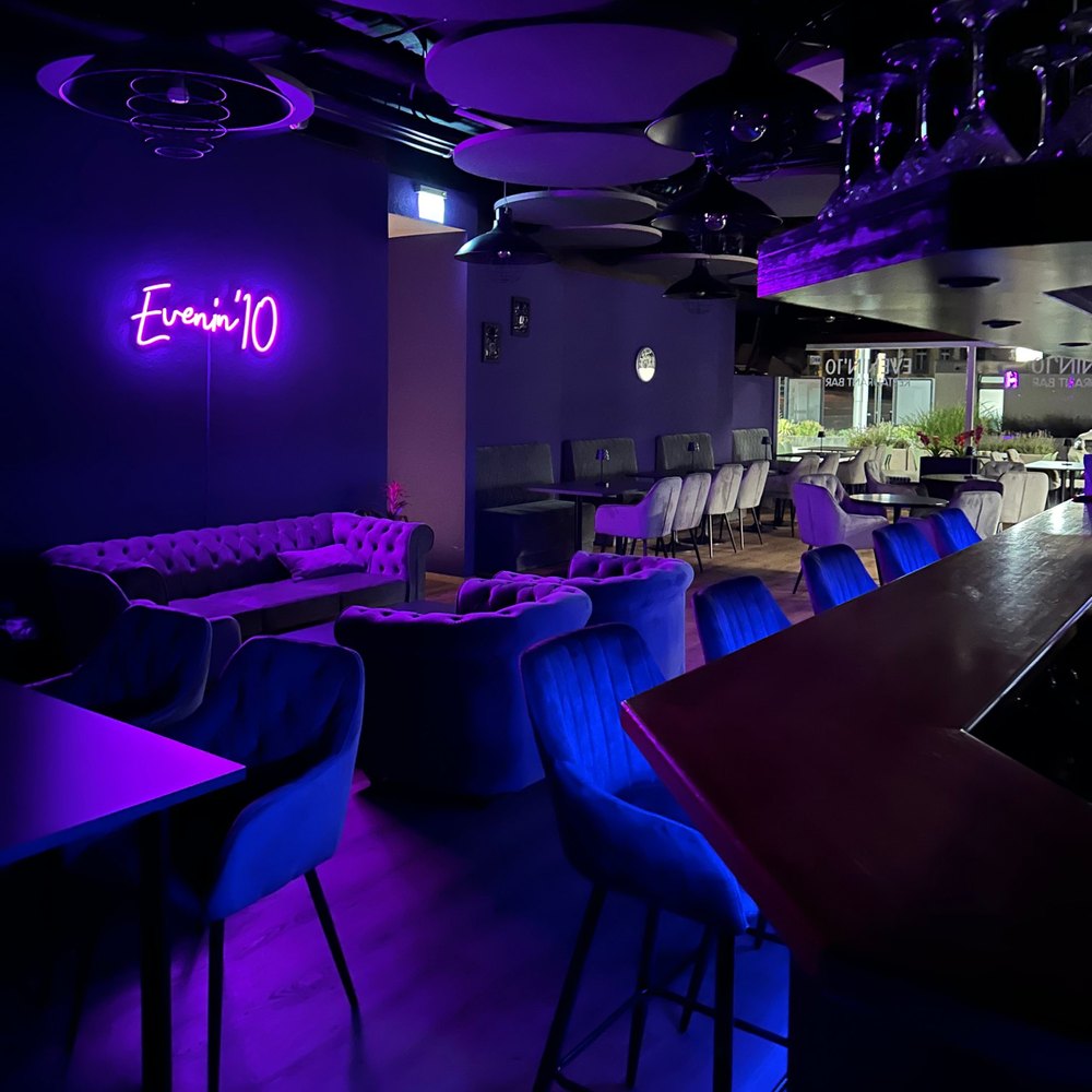 Innenraum des Evenin'10 mit Lounge, Bar und Neon-Schriftzug